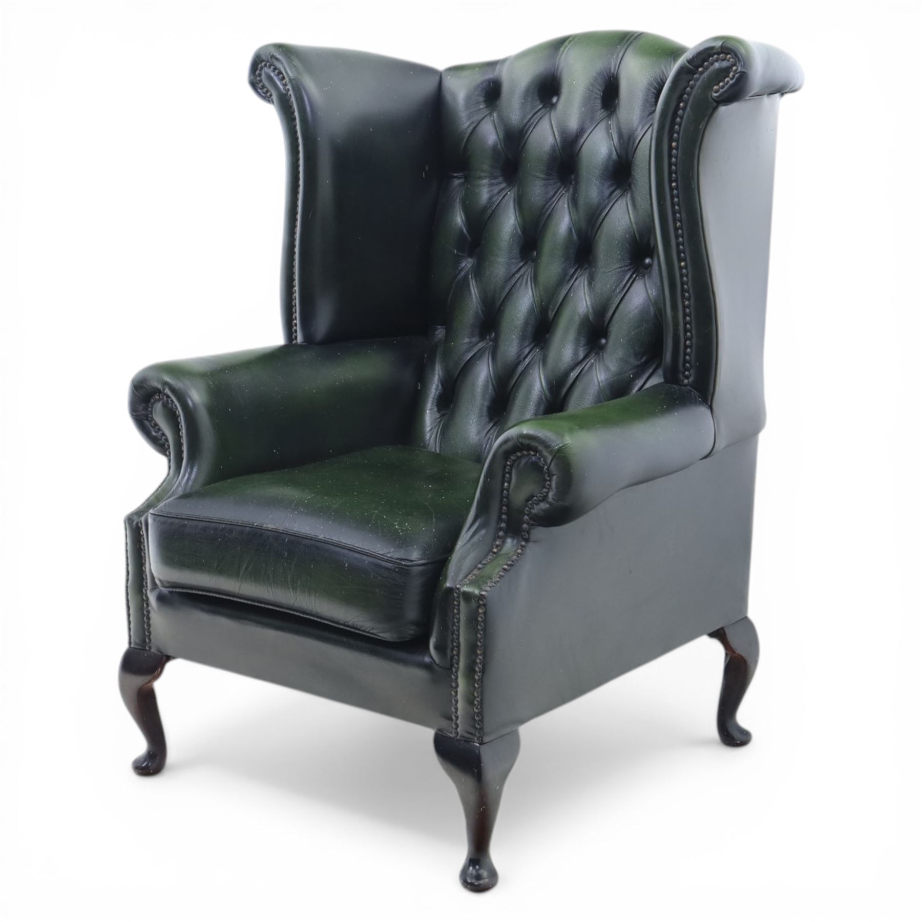 Late 20th century green leather chesterfield style wingback armchair, with deep buttoned back, scrolled wings and arms with studded borders, loose seat cushion, raised on cabriole legs