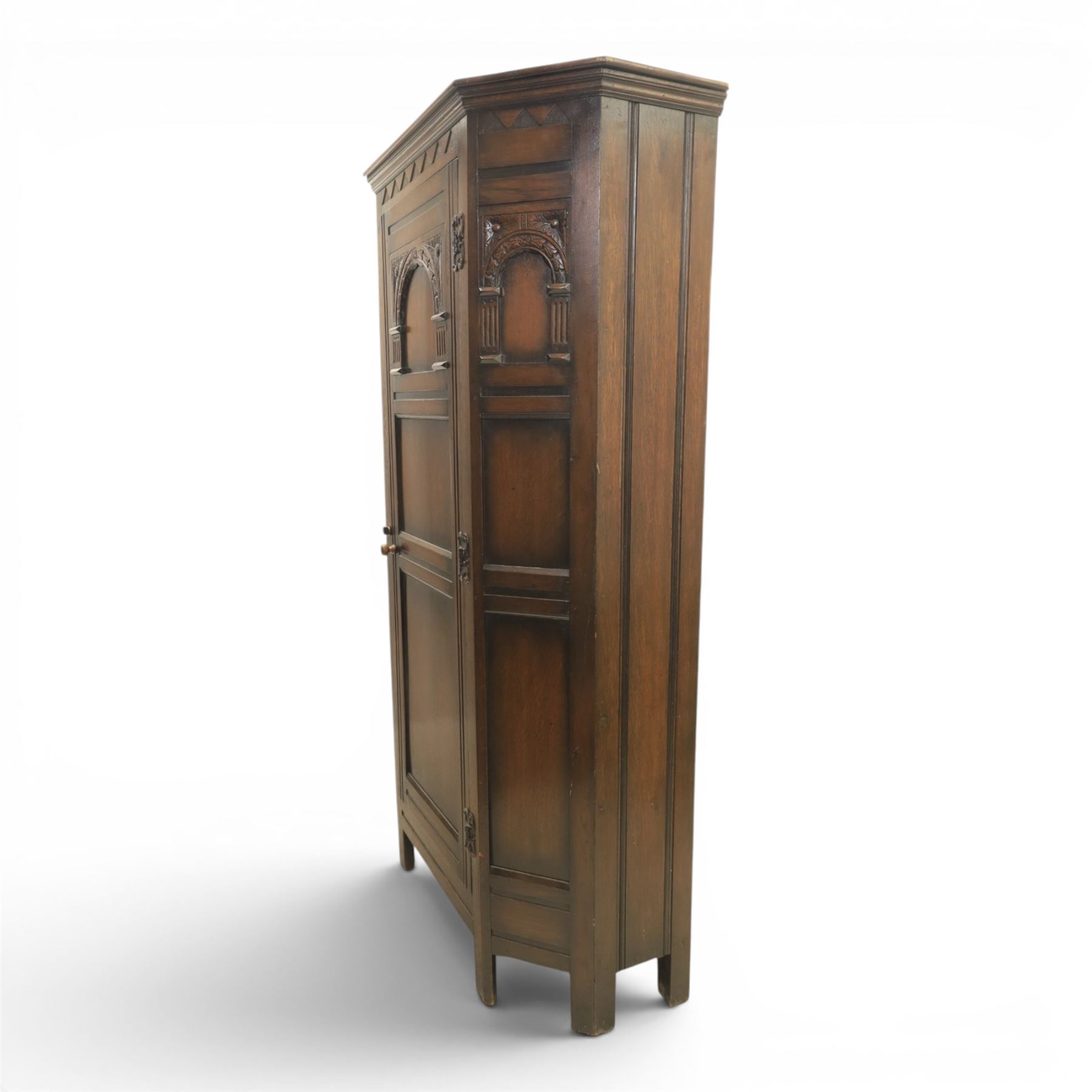 20th century dark stained oak hall robe, cantered sides enclosing a hooks and a shelf, panelled and carved sides, raised on stile supports