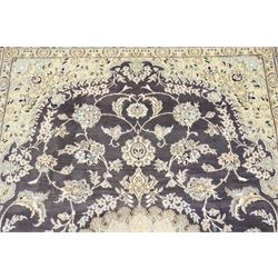 Central Persian Nain hand-knotted carpet, indigo field with central cusped medallion of radiating palmette form, enclosed with an elongated cartouche issuing network of scrolling vine work, arabesques and flowering sprays, surrounding ivory field of conforming design filled with foliate motifs and palmettes, spandrels of complimentary design with angular reserves, within principal border of ivory ground with scrolling vinery rosettes and arabesques, flanked by narrow guard stripes, with cotton fringe ends 