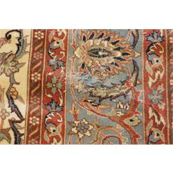 Persian Isfahan ivory and crimson ground rug, the busy field with central floral pole medallion surrounded by foliate motifs and stylised palmettes, the indigo guard line with repeating scrolling plant motifs