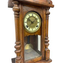 Compact German striking wall clock in the Viennese style c 1910, in a mahogany case with applied carving and turned finials, with a fully glazed door, dial with an ivorine chapter and gilt centre, Roman numerals, minute track and gothic steel hands, 8-day spring driven movement with visible pendulum, wooden rod and spun brass bob. 