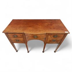 George III Sheraton-style mahogany sideboard, serpentine front fitted with central drawer and flanked by two deep drawers, raised on square tapered legs with spade feet 