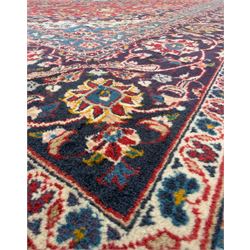 Pair of Persian wool rugs, each with rich red ground, one centred with a diamond-shaped medallion and navy spandrels within a floral field, the other with radiating floral medallion and scrolling foliate motifs, both enclosed by multiple borders with palmette and flowerhead designs, from the region of Kashan 291x376, 299 x 378 