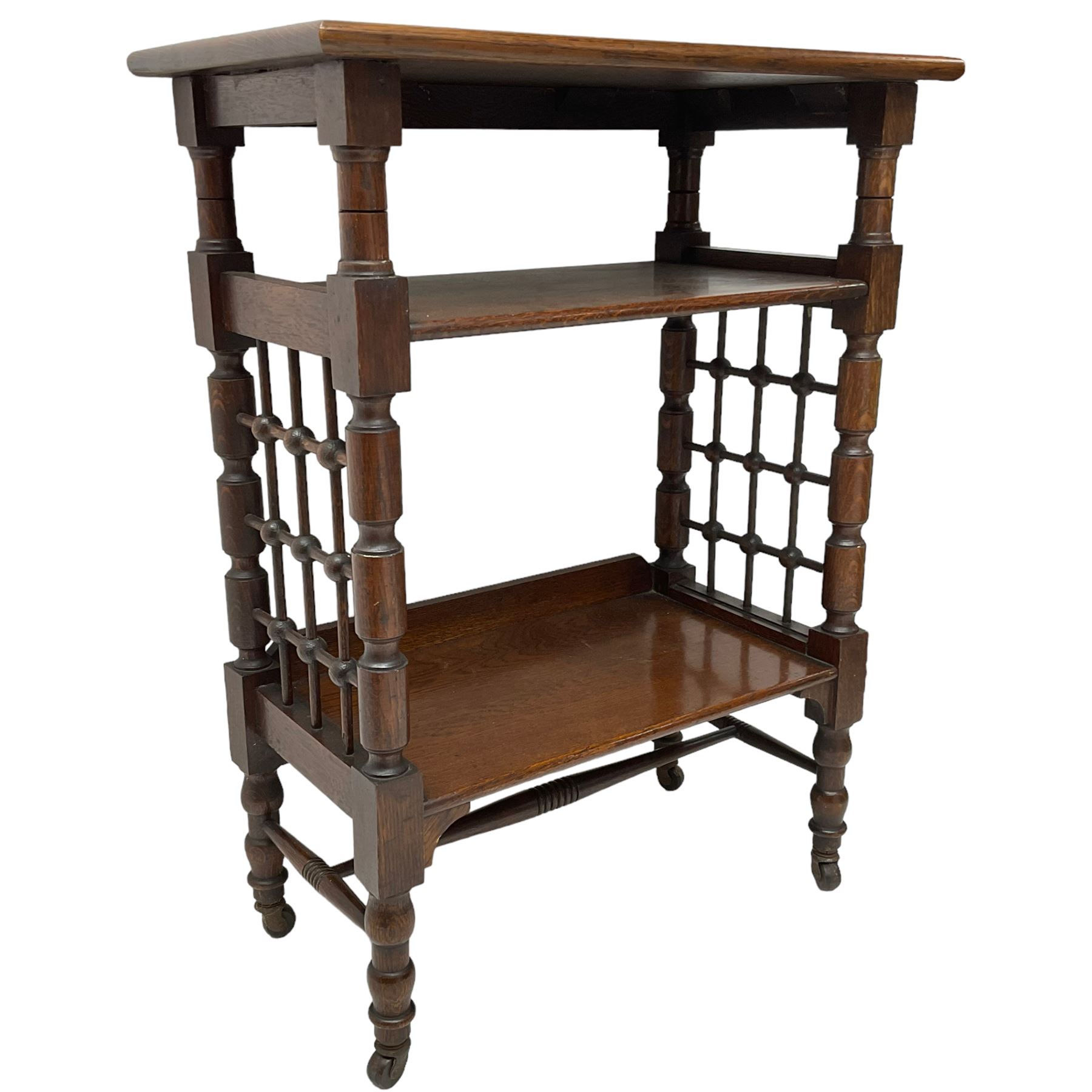 Late 19th century oak three-tier stand or bookcase, on turned supports with lattice sides, on turned feet with castors