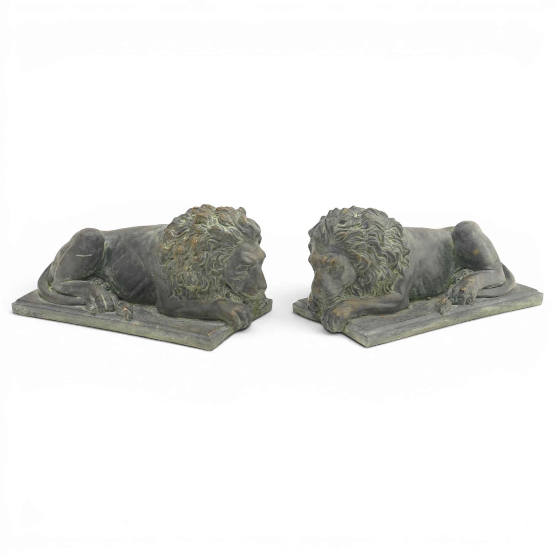 Pair of bronze effect lion figures, recumbent form with carved-style manes and outstretched forepaws, each on a rectangular base, with weathered green patinated finish