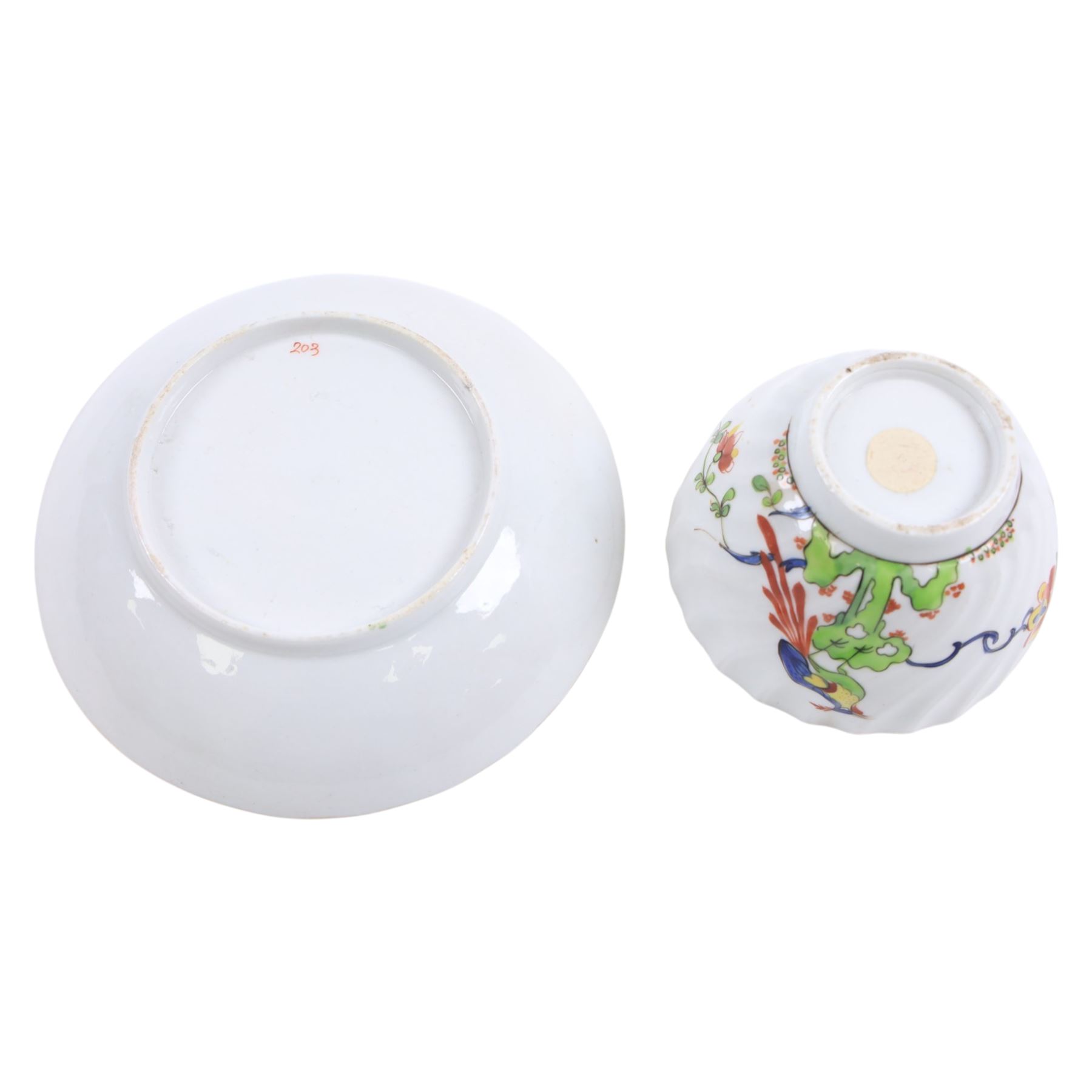 Chamberlain's Worcester teabowl and saucer, each of wrythen form decorated in the Sir Joshua Reynolds pattern, circa 1800, with long tailed Ho Ho bird perched upon green rockwork and surrounded by flowering vines, the saucer with iron red pattern number 203 beneath, teabowl H6cm D8.5cm, saucer D14cm