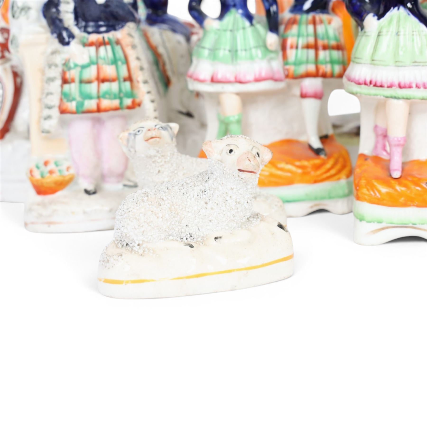 Group of Staffordshire figures, mostly Highland examples, to include figure with bagpipes upon horseback, figure group of Highland Mary and Byron, two figure groups depicting pair of dancers holding flag aloft, two pairs of recumbent sheep, one pair with fags, largest example H30cm