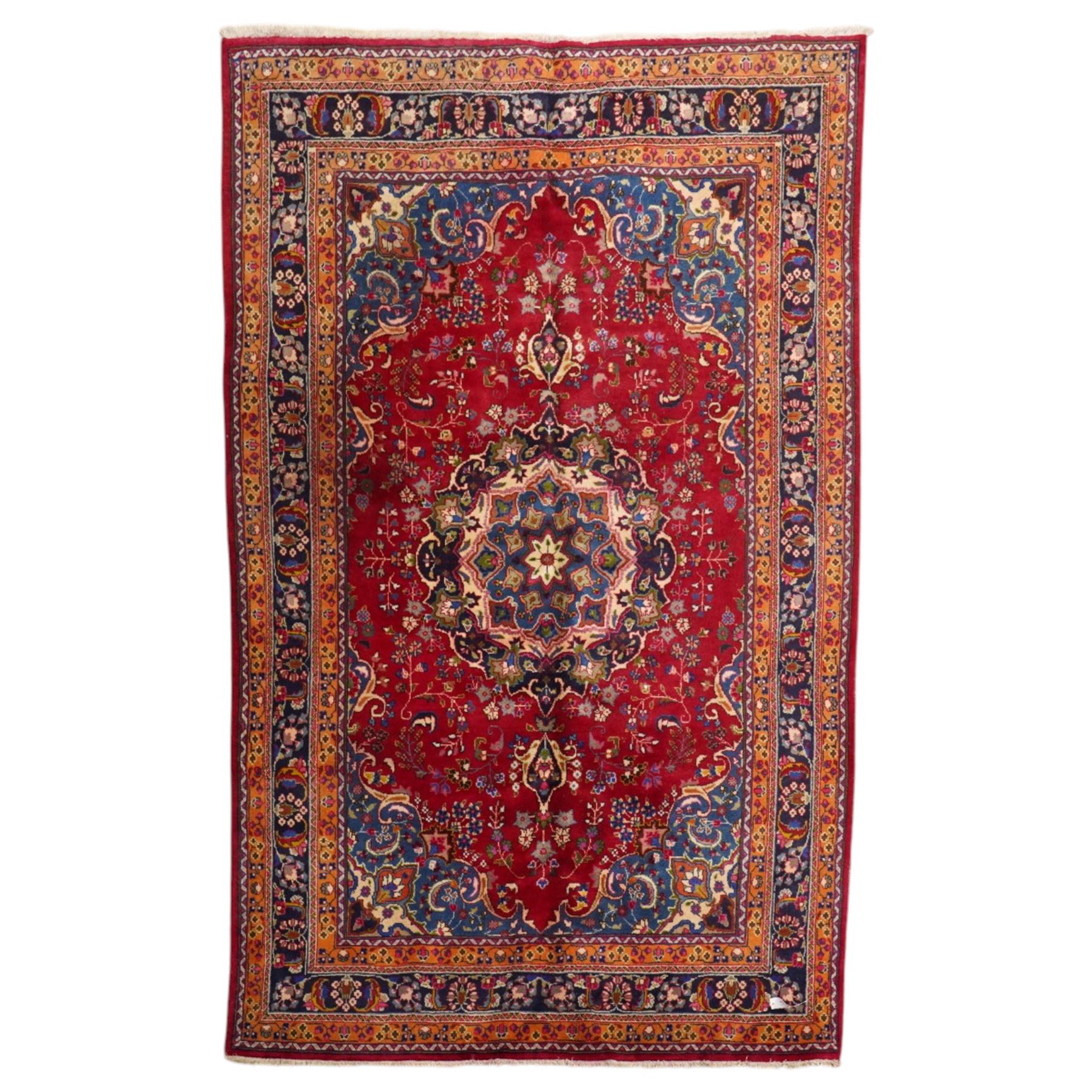 Persian Kashan hand-knotted rug, madder red ground centred by circular floral medallion with pendants, surrounded by scrolling vines, palmettes and flowerheads, dark navy spandrels, enclosed by dark navy floral border with multiple guard stripes