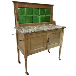 Edwardian oak washstand, raised green tiled back above rectangular marble top, fitted with double cupboard below, on tapering supports with castors