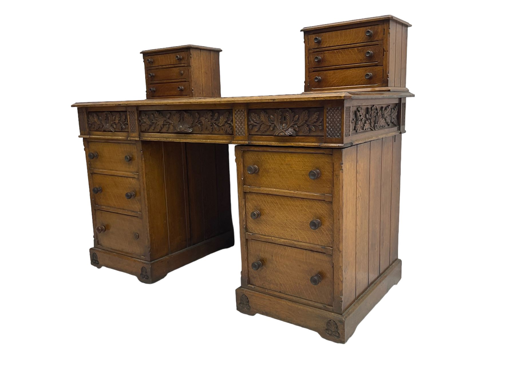 Late 19th century heavily carved oak twin pedestal desk, rectangular top with two raised trinket or correspondence structures each with three drawers, rectangular top over three frieze drawers carved with acorn and oak leaf decoration, each pedestal with three drawers with acorn husk shaped handles