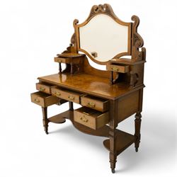 Late Victorian burr walnut veneer dressing table, the arched swing mirror surmounted by pierced scroll cresting, flanked by twin drawers on turned columns, over moulded rectangular top with five drawer arrangement, on block supports with shaped undertier