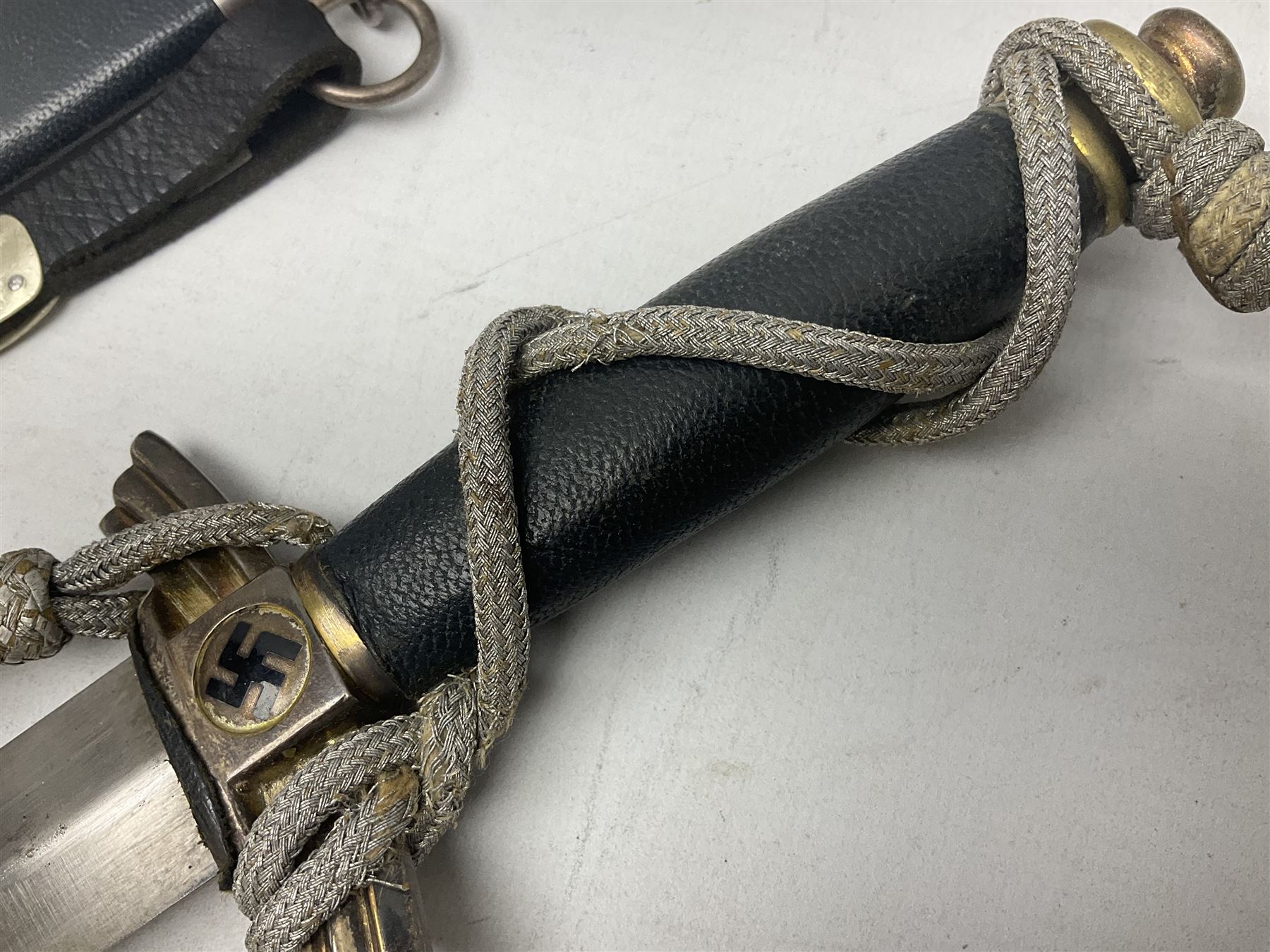 German Paul Weyersberg & Co Solingen DLV flyers dagger with 18cm steel blade, plated brass/tombac downswept cross-piece and pommel and leather covered grip, in leather and plated brass/tombac scabbard with leather hanger strap and silvered knot L35cm overall. Auctioneer's Note: After WWI Germany was forbidden an air force by the Treaty of Versailles however the Deutscher Luftsport-Verband (German Air-sport Association) was formed in March 1933 from various sports flying clubs and had branches for aeroplane, gliding and balloon flying. Under cover of the sporting DLV, many future Luftwaffe pilots trained to fly. DLV was embodied with the NSKK in March 1935 and on 1st March 1937 Luftwaffe was formed.