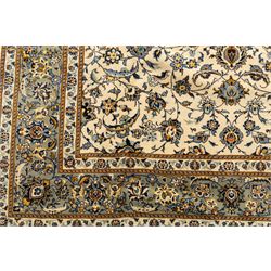 Central Persian Kashan hand-knotted rug, ivory field intricately decorated with an all-over design of scrolling vines, palmettes, and stylized lotus motifs in shades of soft blue, pale gold, and indigo within floral borders