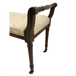 George III style walnut duet piano stool, scrolled supports with flower head carved terminals, on turned supports with brass cups and castors