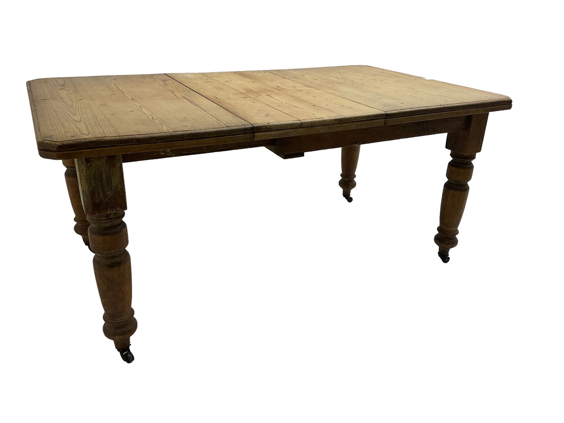 Late Victorian pine extending dining table, rectangular moulded top with canted corners and additional leaf, on turned supports with brass castors 