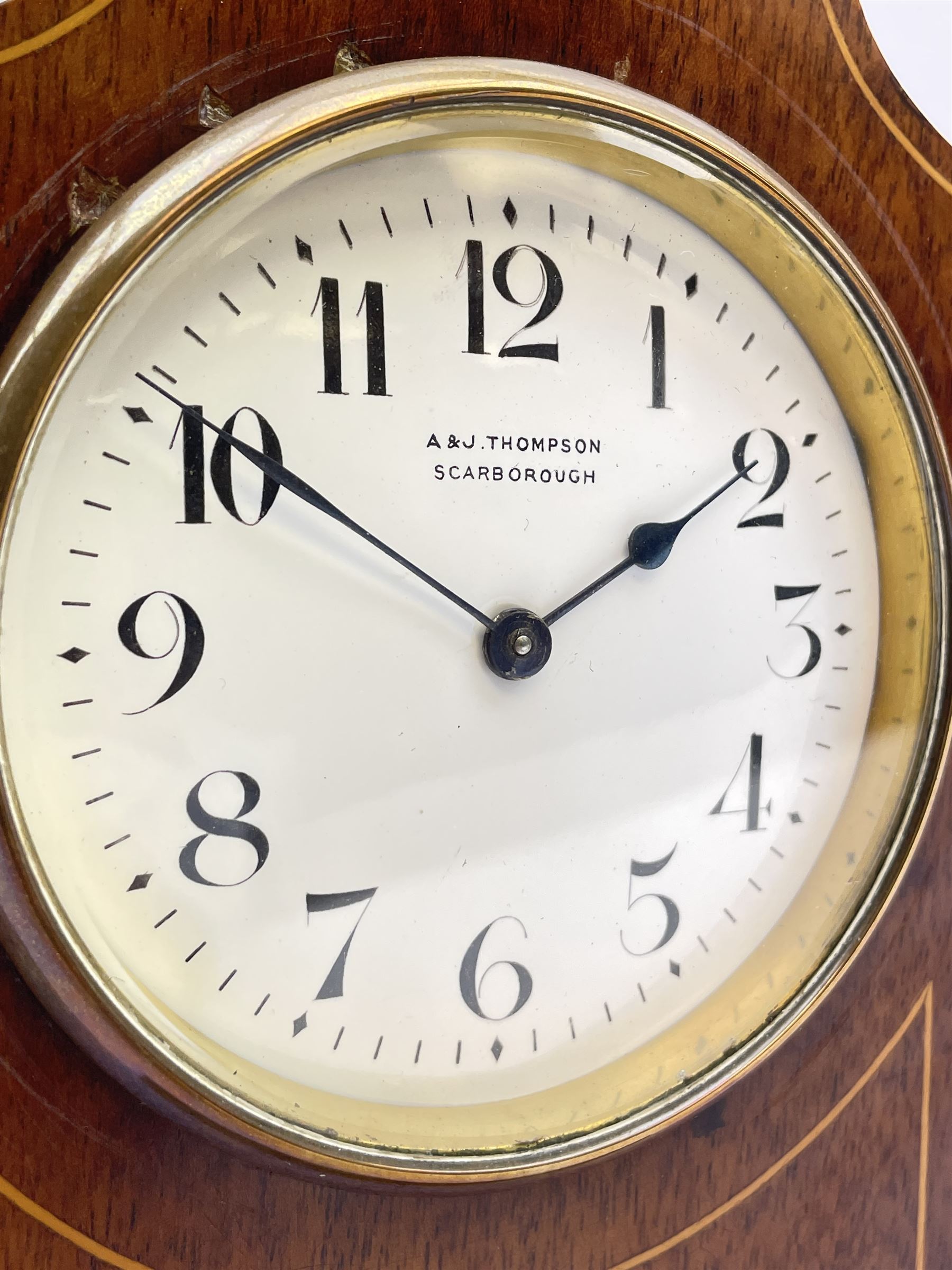 Edwardian inlaid mahogany mantel clock, stepped cavetto and arched top pediment, circular white enamel Roman dial signed 'A & J. Thompson, Scarborough', the front inlaid with fan motif, raised on globular brass feet, single train driven movement by 'R & Co. Paris'