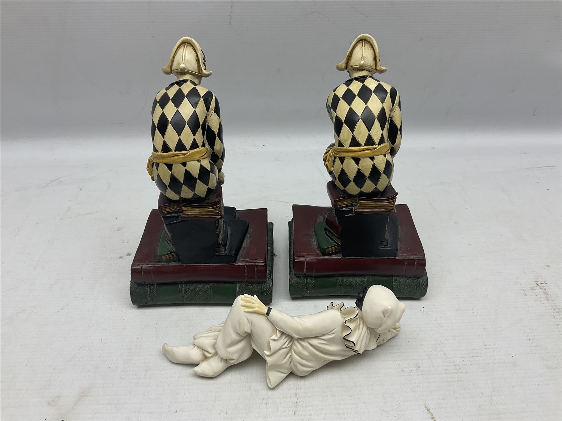 Pair of early-mid 20th century figural composite bookends modelled as harlequin court jesters sat upon stacks of books, H20cm together with a figure of a jester signed Vivian C (3)