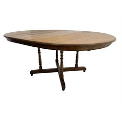 Early 20th century oak dining table, circular extending top with telescopic action, on four pillar base with x-framed platform, turned feet