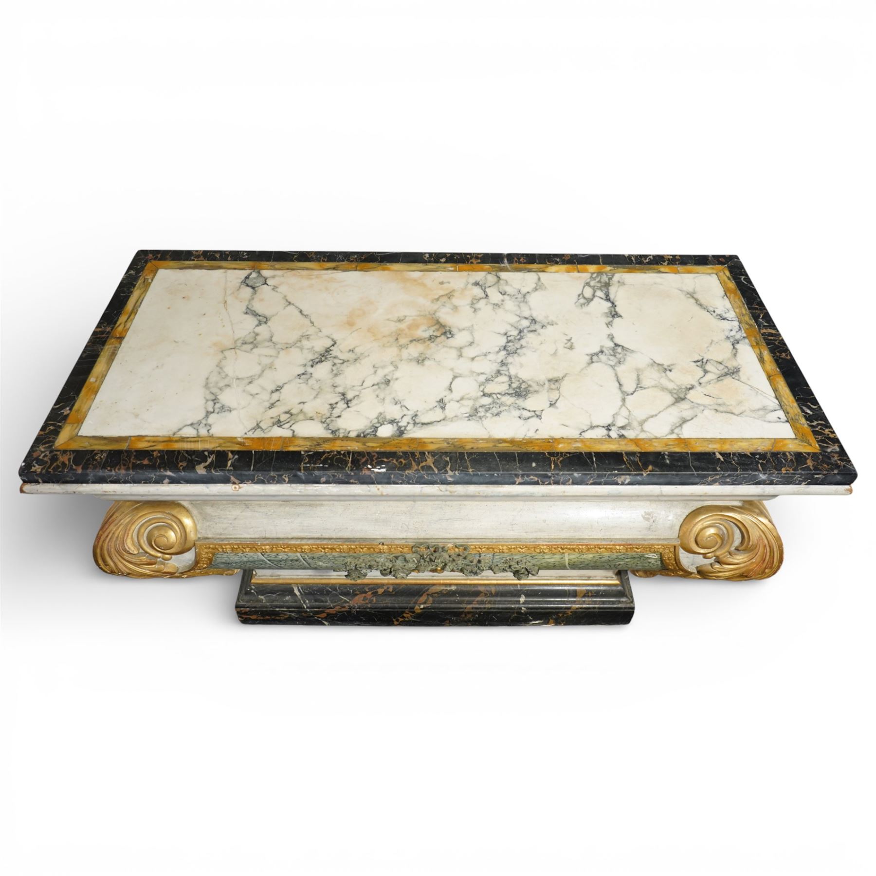 A 20th century Italian Neoclassical console table of architectural pedestal form, inspired by Roman architectural prototypes, with marble top and simulated marble scagliola-type finish; the rectangular marble top with grey veining within a black and yellow marble border, above a pedestal base finished in a finely executed faux-marble surface and enriched with parcel-gilt scrolling acanthus terminals, floral garlands, a central ribbon-tied motif in relief, and further raised flowerheads and a central gilt monogram, terminating in a stepped plinth base