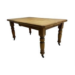 Late Victorian pine extending dining table, rectangular moulded top with canted corners and additional leaf, on turned supports with brass castors 
