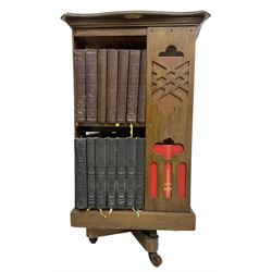 Late Victorian revolving bookcase, shaped square top over fretwork supports of geometric and arcade design, on a swivel action base with ceramic castors