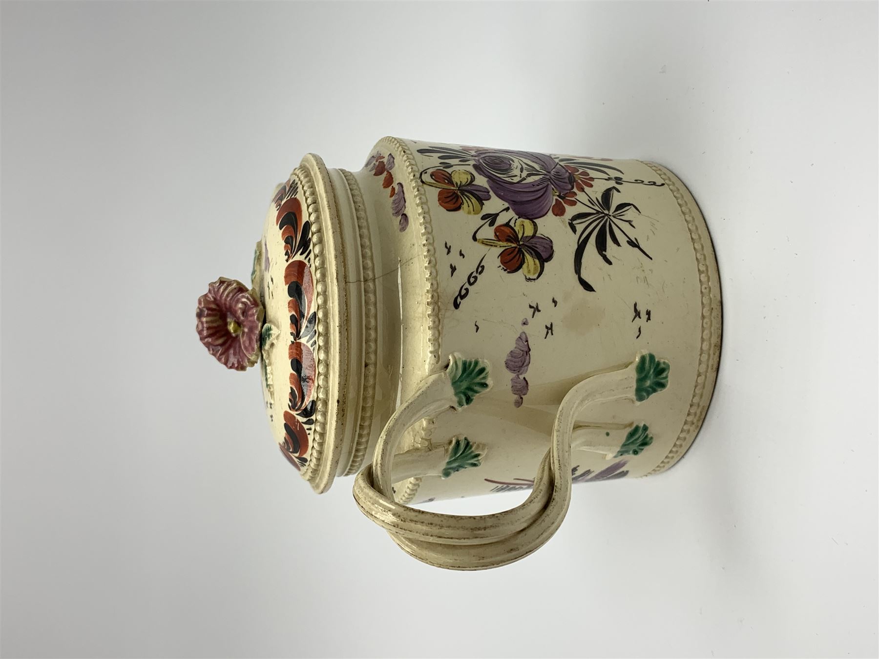 18th century creamware teapot, probably Leeds, with reeded entwined handle and floral finial to the cover, the body with hand painted polychrome decoration of figure to one side, and floral spray to the other, collectors paper label beneath inscribed Leeds Pottery, H11.5cm