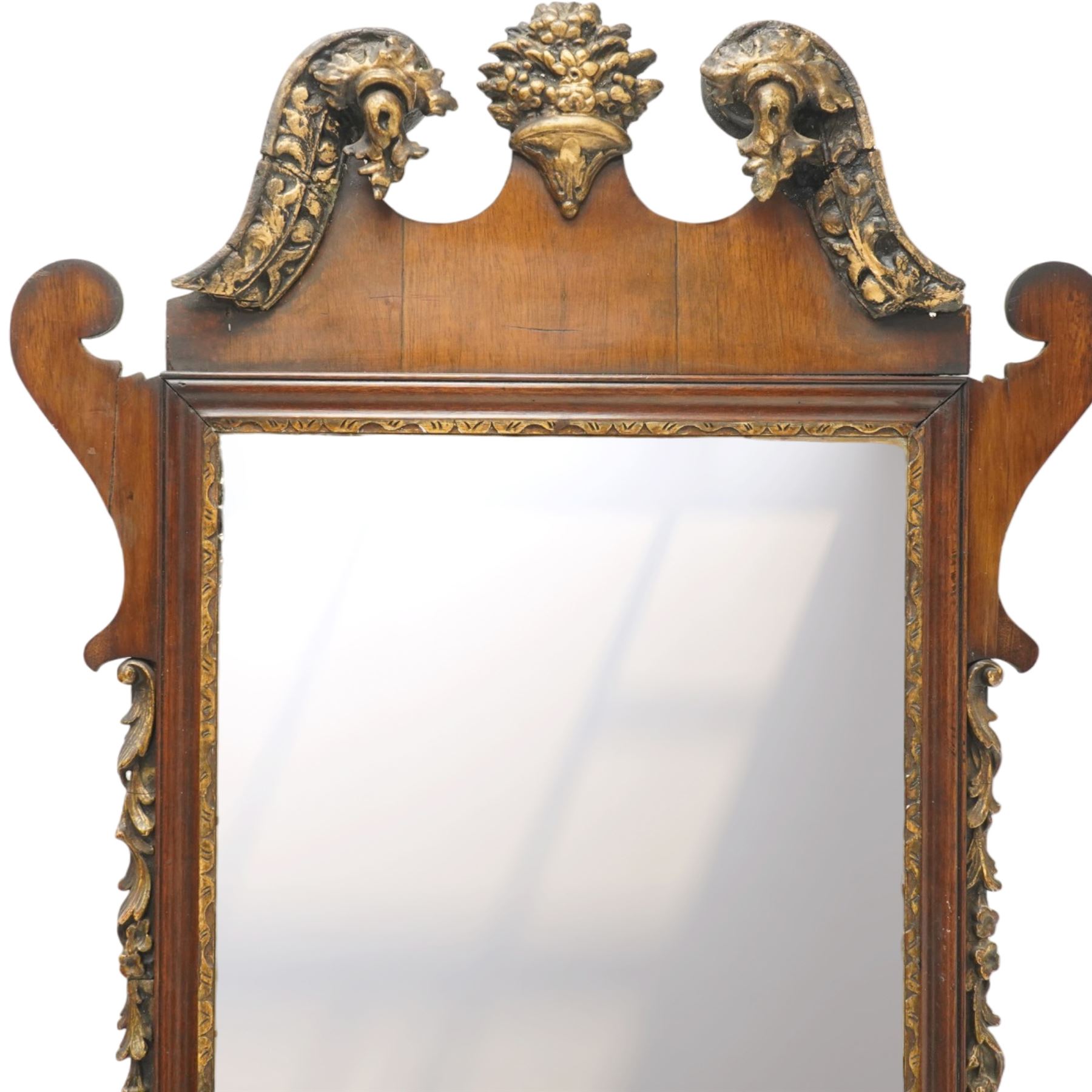 19th century Chippendale design mahogany fret mirror, broken swan neck pediment of foliate design with century bouquet in gilt finish, the rectangular bevelled plate flanked by trailing bellflower motifs, over a shaped terminal