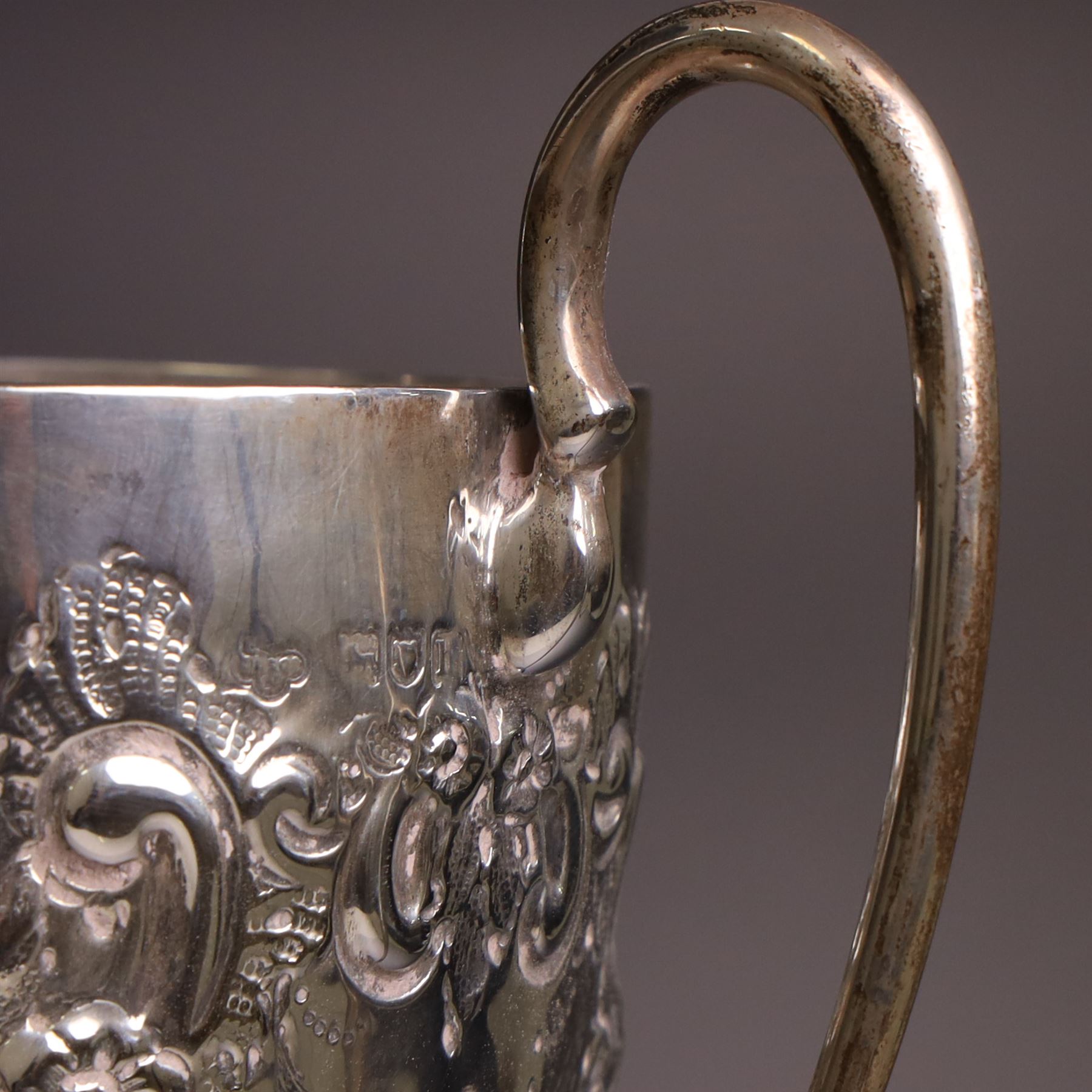 Edwardian silver twin-handled trophy, with embossed floral and scrolling decoration, upon a knopped stem and circular foot, hallmarked Goldsmiths & Silversmiths Co Ltd, London 1903, upon a black plinth, including plinth and handles H32cm