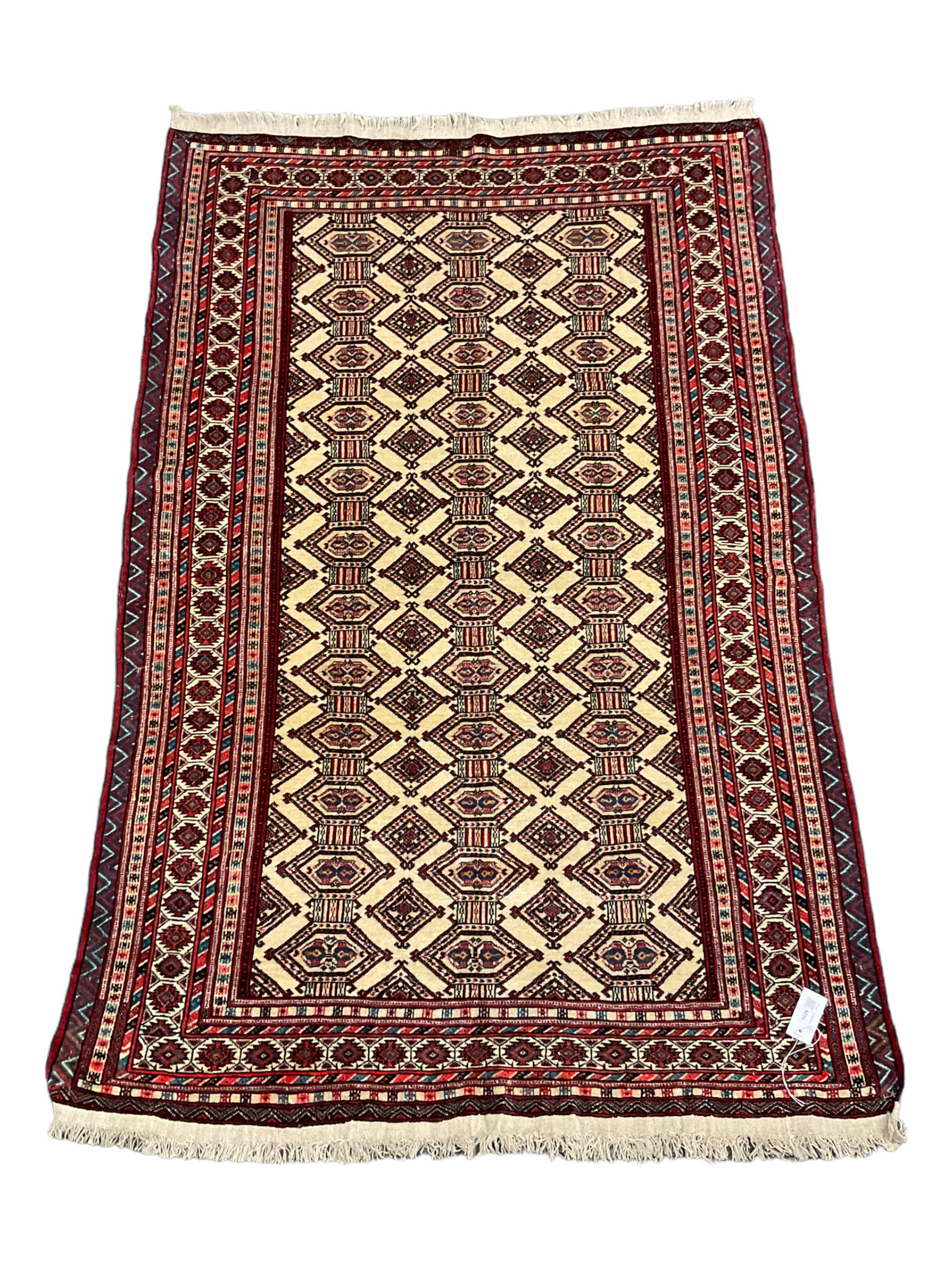 North East Persian Turkoman rug, ivory ground field decorated with repeating Gul motifs, multi-band border decorated with geometric patterns and motifs