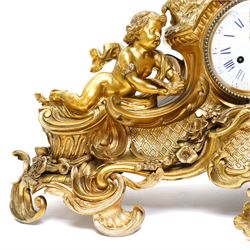 French-large late 19th-century 8-day Louis XV style gilt bronze mantel clock, with a cast rococo style case, elaborate C-scrolls, shells, and floral sprays, surmounted by a seated putto and goat symbolising pastoral love, flanked by two further seated putti on a scrolled foliate base, 5