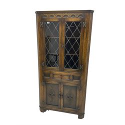 Jacobean design oak corner display cabinet, lunette carved frieze over lead glazed doors, fitted with drawer and double cupboard below