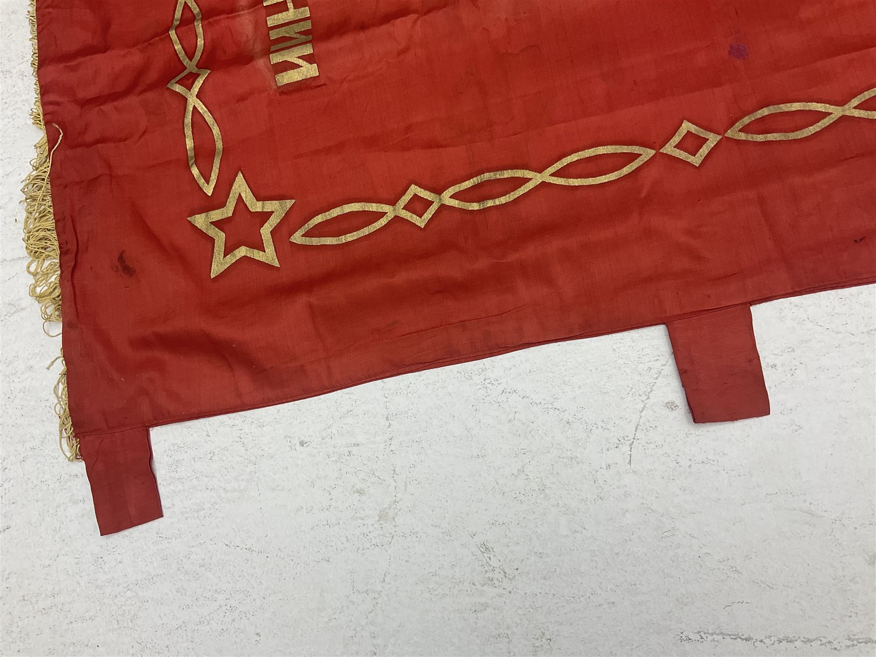 1970s Soviet banner printed in gold on a red ground, roughly translates as 'Transferable Banner - To the winner in the Socialist Competition' and 'Work Study Live by Communism' verso; wreath of wheat ears to either side; tassels on three sides 110 x 155cm