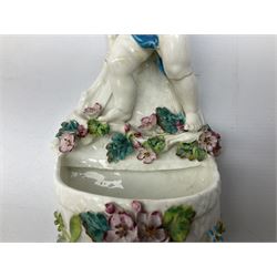 Victorian wall pocket by Moore Brothers retailed by T.Goode modelled as a semi nude white glaze cherub with turquoise ribbon, with encrusted floral decoration, the reverse stamped ‘T.Goode & Co.’, H32cm