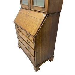 George III oak bookcase on bureau, the double arched top enclosed by two shaped glazed doors, fall-front concealing fitted interior, over four graduating cock-beaded drawers, on bracket feet