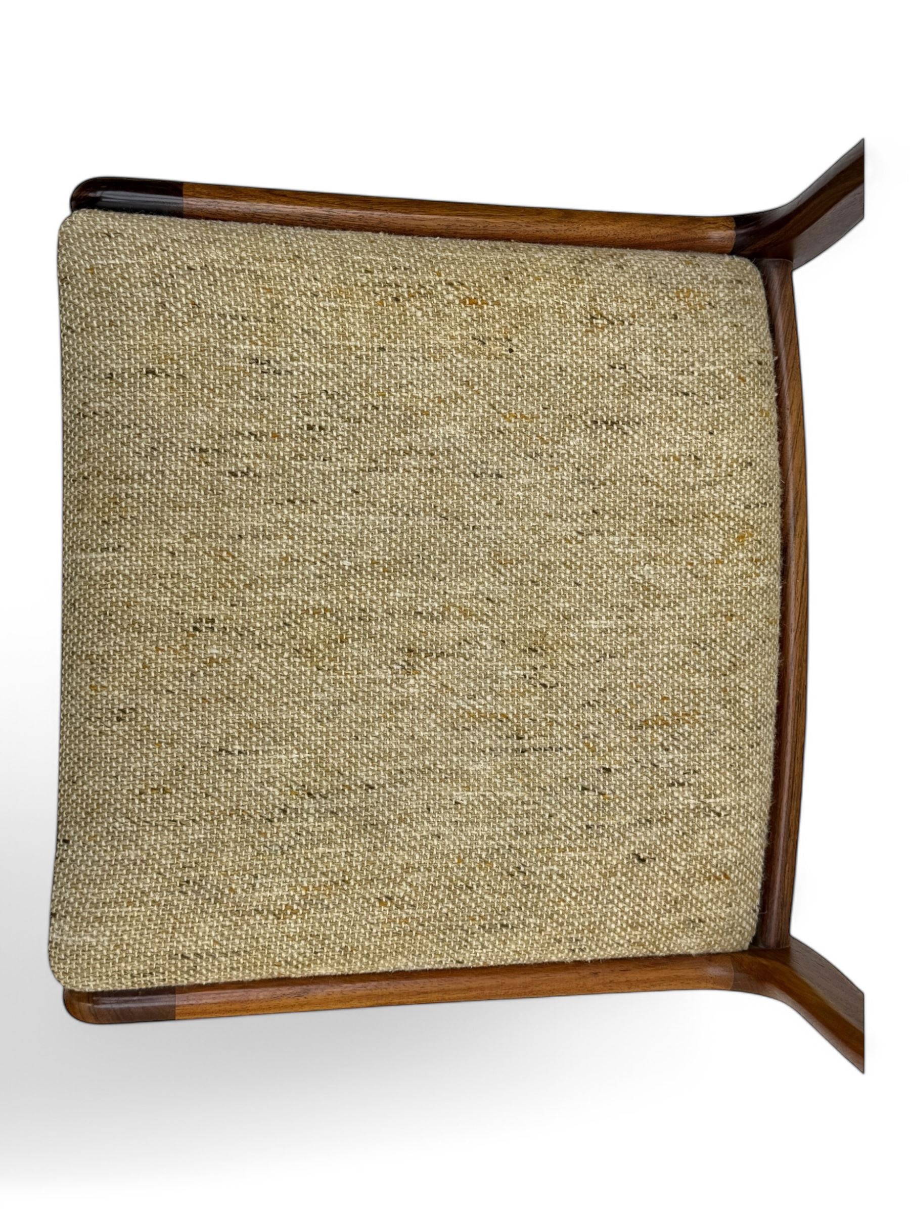Johannes Andersen for Uldum Mobelfabrik - set of eight Danish teak dining chairs, each with open back rests with curved edges, upholstered seats in a neutral woven fabric, raised on tapered supports