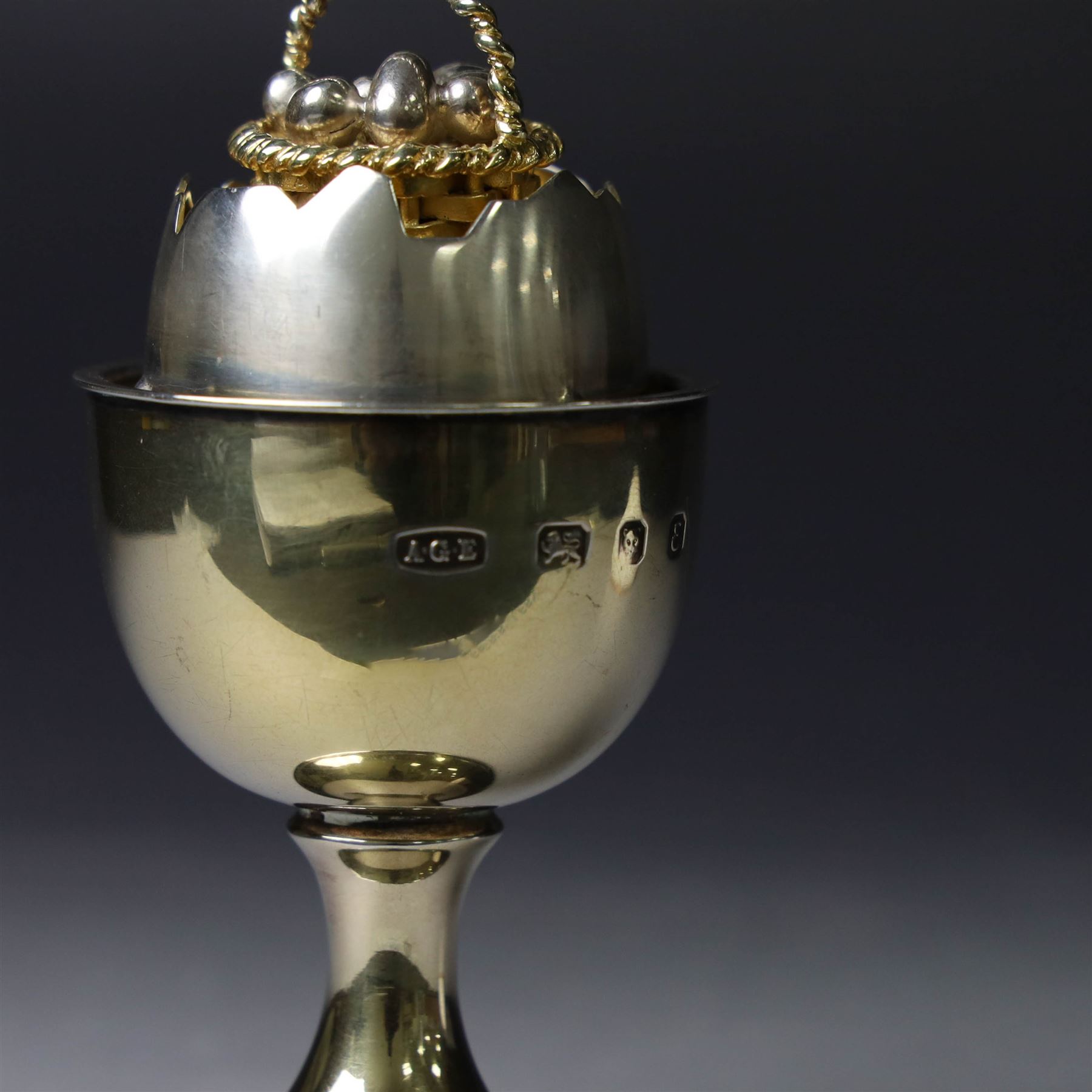 Late 20th century silver-gilt novelty surprise egg by Anthony Gordon Elson, the egg cup containing a  removeable shell, lifting to reveal a parcel gilt egg basket beneath, hallmarked Anthony Gordon Elson, London 1979, H11cm