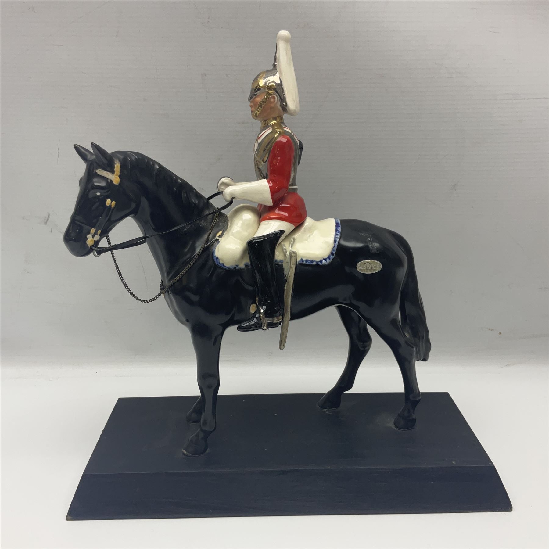 Mounted Lifeguard upon a black horse, in the style of Beswick, upon a wooden plinth, H31cm
