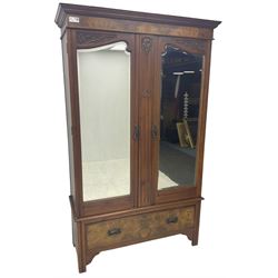 Edwardian figured walnut double wardrobe, carved with foliate decoration, fitted with two bevelled mirror doors, single drawer fitted to base
