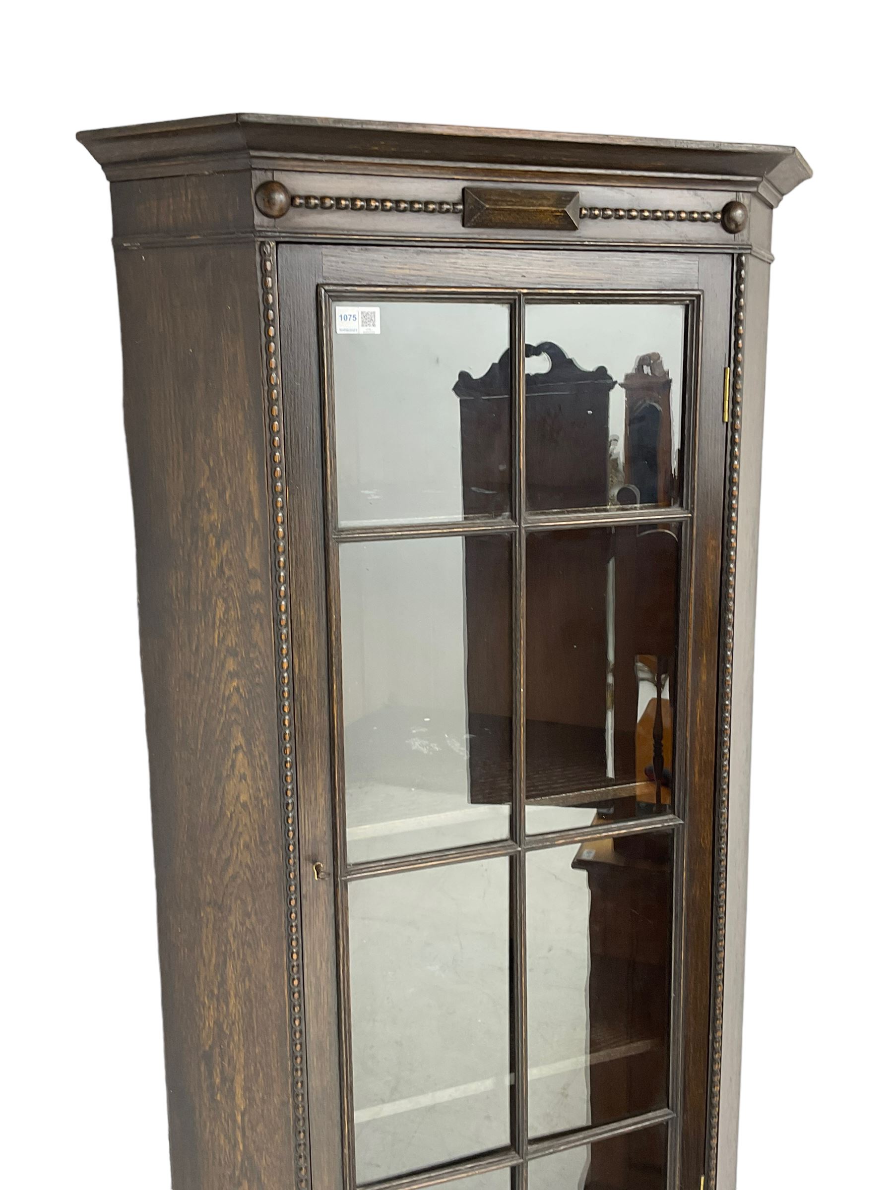 Early 20th century oak corner display cabinet, enclosed by glazed door, on spiral turned supports joined by undertier 