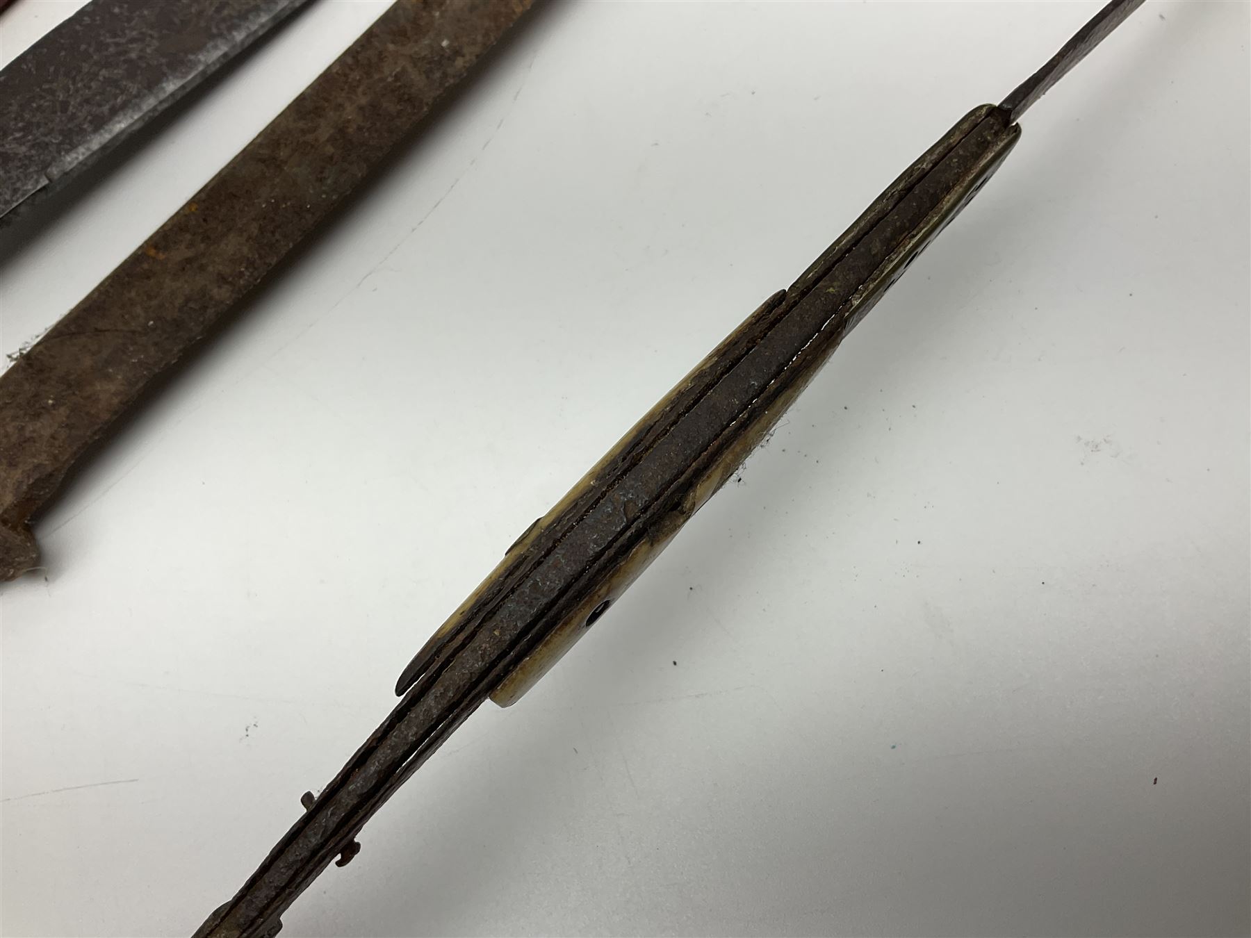 19th century continental folding knife with 15.5cm single edged blade, the pierced brass and iron handle with remains of horn grips L21.5cm overall closed; turned horn handled knife with foliate engraved blade; battlefield relic German 1884/98 knife bayonet; iron spear head; leather covered swagger stick; and two-piece gun cleaning rod