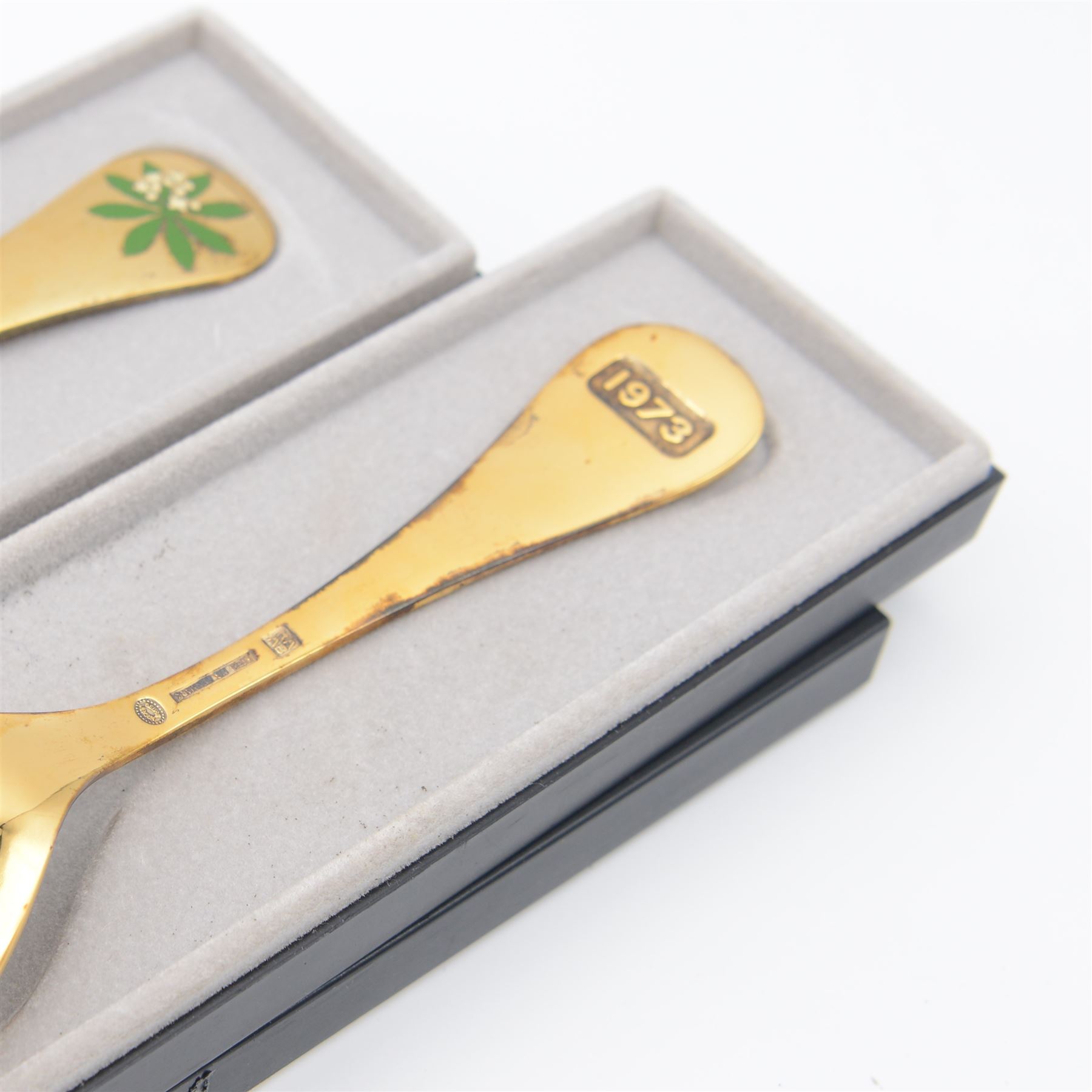 1920s Danish silver spoon and fork set by Georg Jensen, stamped 925S Georg Jensen, with import marks for London 1926, contained within fitted tooled leather retailers case, together with two Georg Jensen silver-gilt year spoons, comprising 1975 example with enamel woodruff flower decoration, with personal inscription verso and a 1973 example with enamel marigold decoration, both boxed