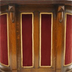 Arts & Crafts oak D-shaped bar, moulded edged counter above a front with velvet applied panels, the back with shelving, raised on a plinth base