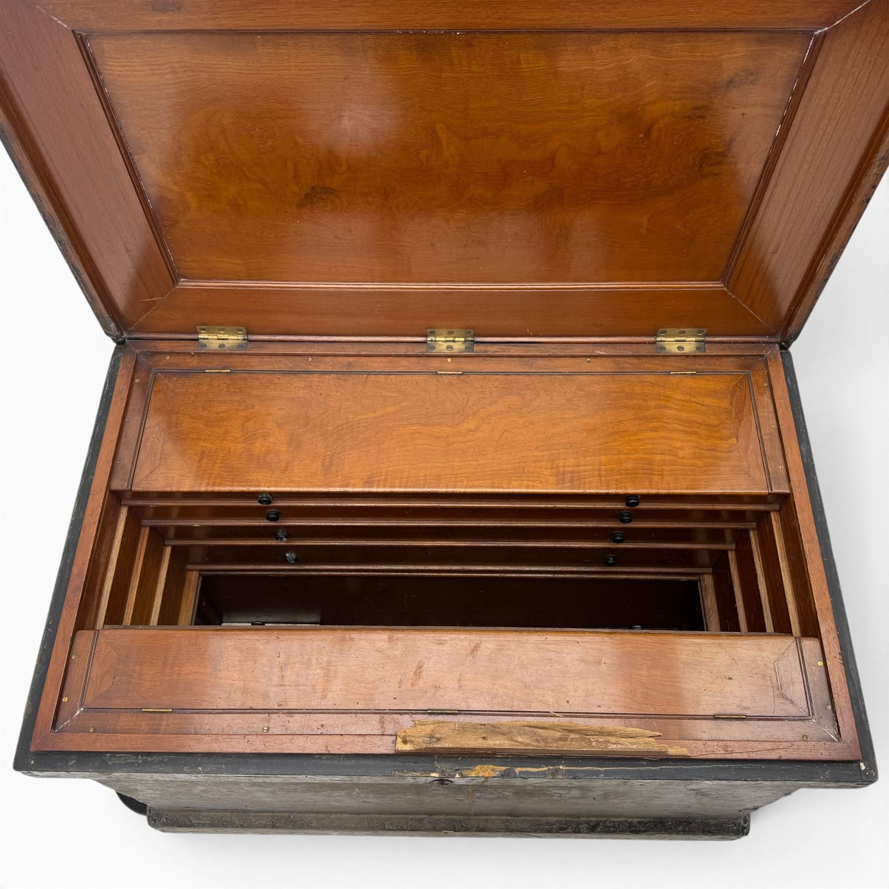 20th century black painted camphorwood lined tool chest, rectangular hinged lid over moulded edge, black painted exterior with iron straps and carry handles, the interior fitted with sliding lidded trays and drawers with turned handles, containing an assortment of hand tools