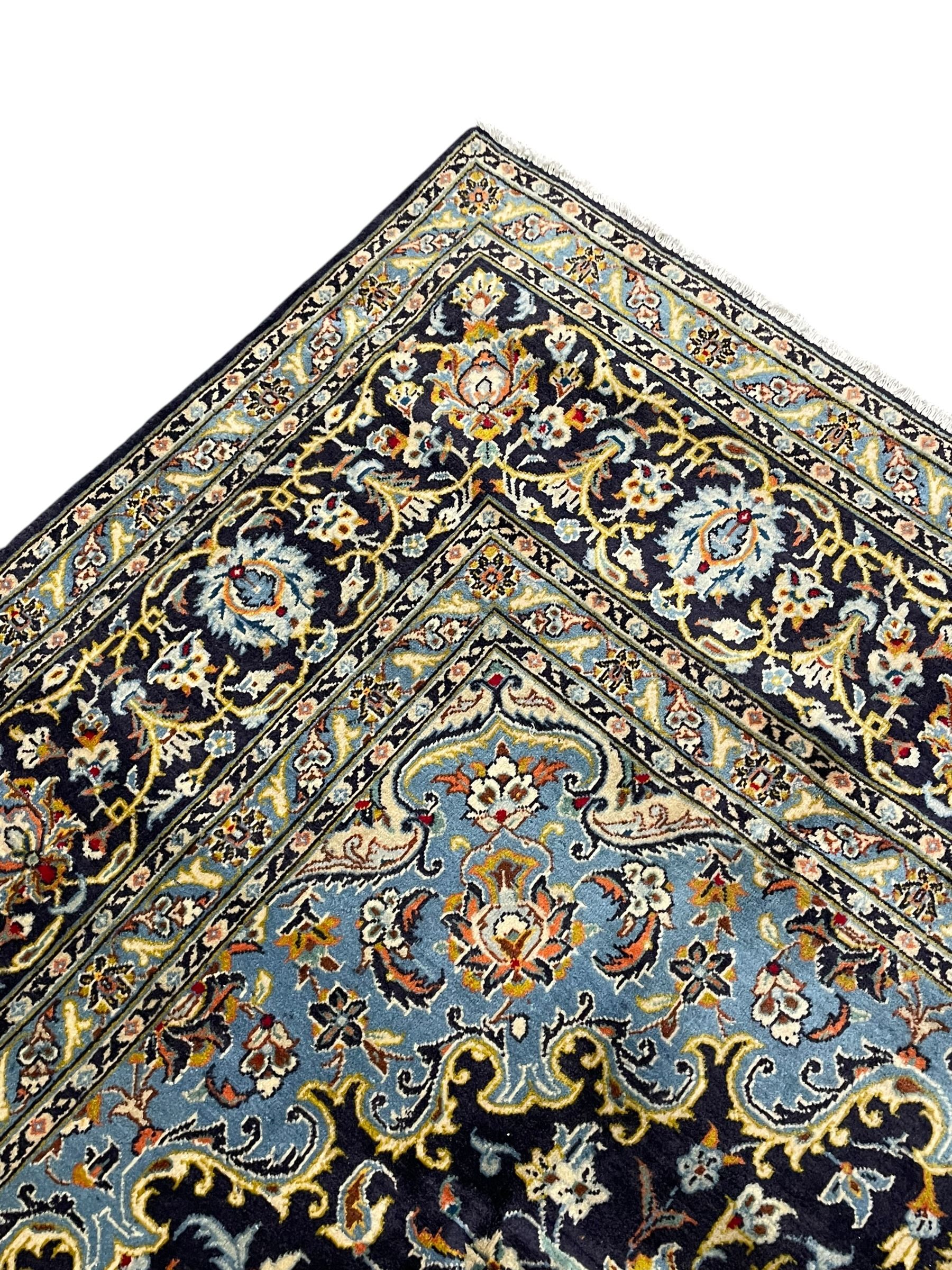 Persian Kashan indigo ground carpet, floral pattern light blue ground central medallion and spandrels, the fielding decorated with interlacing leafy branches and palmettes, the repeating floral pattern border enclosed within guard stripes