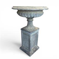 Pair of cast stone garden urns of kylix form on pedestals, the broad egg-and-dart moulded rim over a shallow gadrooned underbelly, with waisted tapering base, raised on matching plinth bases with faux panelled facia