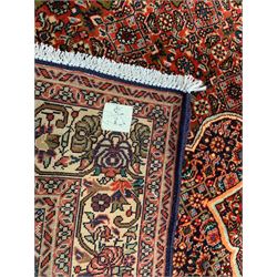 Persian Bidjar crimson ground rug, thick woollen pile, the field decorated with repeating Herati motifs within cusped outlines, the guarded border decorated with repeating flower head motifs