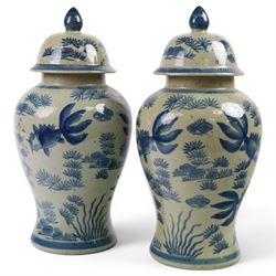 Pair of Chinese blue and white jars and covers, of baluster form, painted with fish and fo...