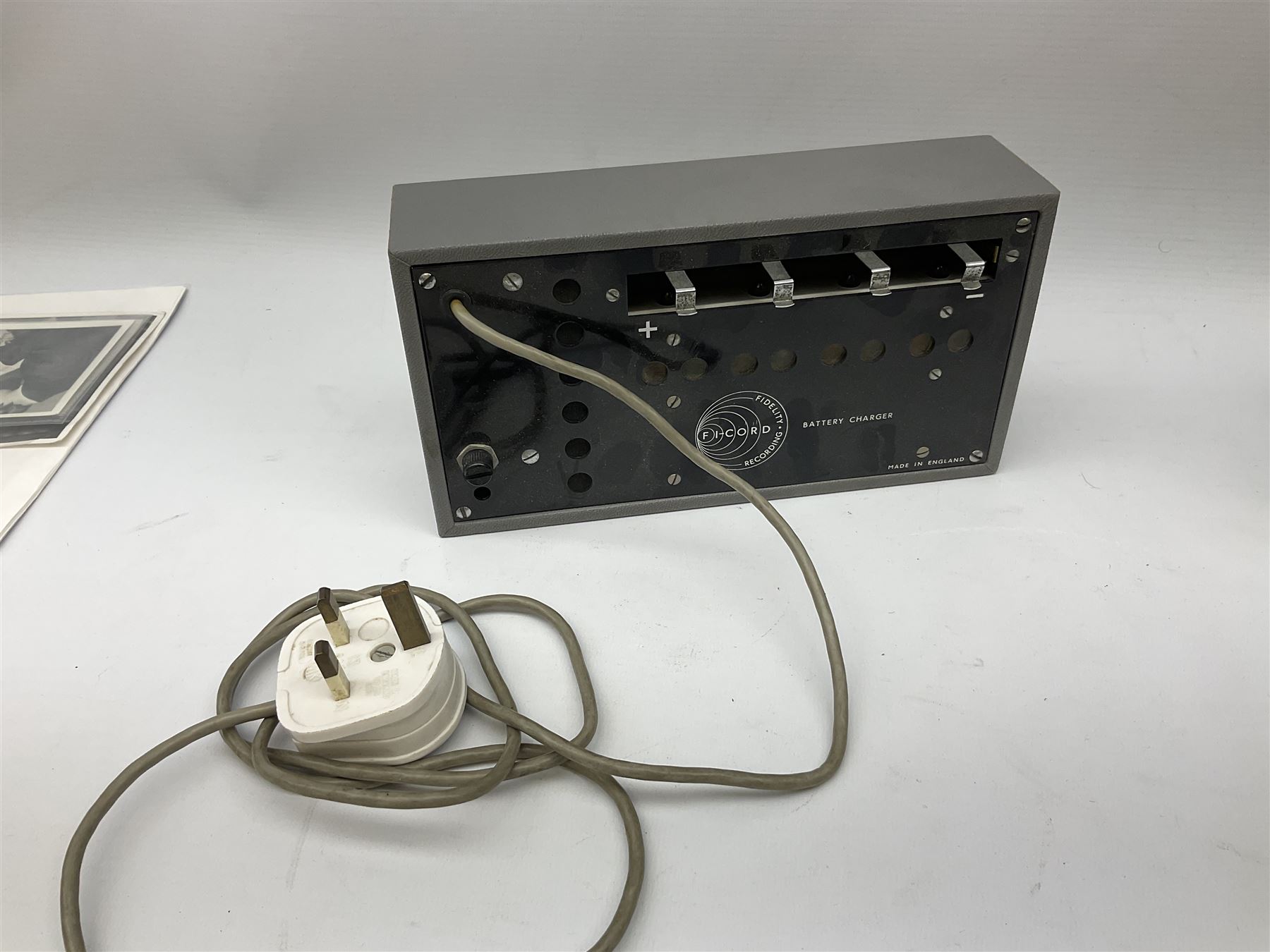 John Lennon interview recording conducted by John Hill student of Hull University on the 16th October 1964 at the A.B.C. Theatre Hull on behalf of the university newspaper 'Torchlight'. The interview lasts eight and a half minutes. It catches John in an upbeat breezy mood answering questions about the following topics: the song writing process ('sometimes you get an idea ....I dunno....my left leg.... and then write about that....'), recording (.... 'they just say - you're recording on such and such a date and they hope we turn up with some good songs written ....'), an alternative career path (.... 'I'd probably just have been a lay-about....'), failing at college (....'some other lads did my exams for me ....'), reading matter ( Clockwork Orange, Alice in Wonderland), his books of prose, tastes in music, the Blues, The Rolling Stones, being a Beatle vis-a-vis anonymity ('Whatever I'd be I'd choose to be rich .... who wants to walk down the street?').
The interview was recorded on 1/4 inch Emitape on a Fi-Cord Fidelity Recording machine. The reel-to-reel tape comes in its original Emitape plastic box and is accompanied by the Fi-Cord reel-to-reel machine on which the interview was originally recorded. Also included in this lot are a copy of the 'Torchlight' newspaper from 21st November 1964, two photographs of the interviewer with John Lennon (the interviewer is pictured to the left of John Lennon in the photograph in which John is signing a sketch) and one photograph of Paul McCartney with another reporter, the largest measures 12 x 16.5cm and a transcript of the interview. The recording is also accompanied by the original Fi-Cord tape recorder with microphone, four original 2v batteries and battery charger. The tape recorder has been adapted to take 3xAA batteries and the 2v battery charger is fitted with a standard UK 3-pin AC plug. The interview was recorded in the press room prior to the Beatles concert at the A.B.C. Theatre and is sold with copyright.