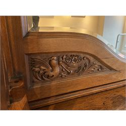 Late 19th century Arts & Crafts period oak mirror back sideboard, shaped bevelled mirror back carved with foliate scrolls and flower heads, down swept supports with elongated club-shaped uprights, moulded rectangular top over two drawers and three cupboards, the drawer fronts with copper handles decorated with sailing ships, panelled doors carved with mythical beasts, flowerheads and foliage, on moulded block feet