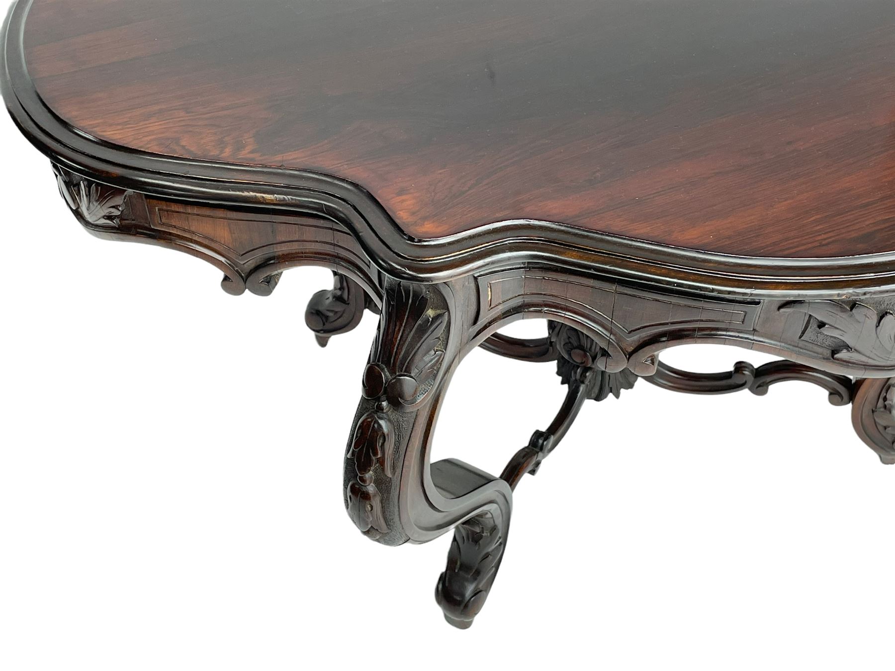 19th century Irish rosewood centre table, the shaped and moulded top over shaped apron carved with scrolled foliage, on serpentine supports carved with bell flowers, the supports united by anthemion carved finial and s-scroll x-framed stretchers